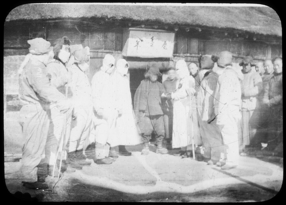 Men in protective gear escort a man as people look on