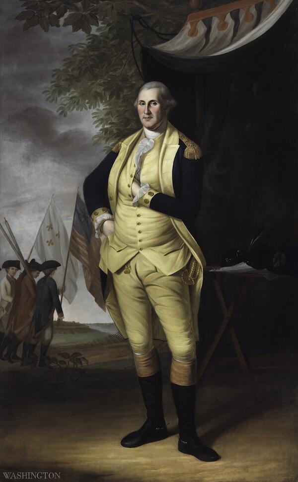 George Washington stands before a military tent with his left hand in his waistcoat and his writing desk with quill and paper behind him and American troops carrying flags in the background.