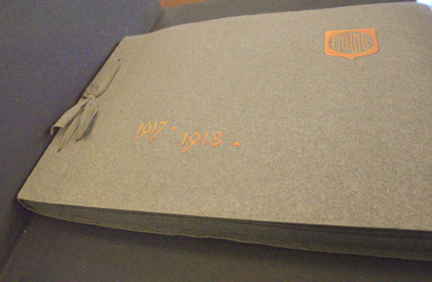 Rectangular photo album tied with ribbon on the short end with a gold shield with FRANCE in the upper right corner and 1917-1918 in gold on lower left